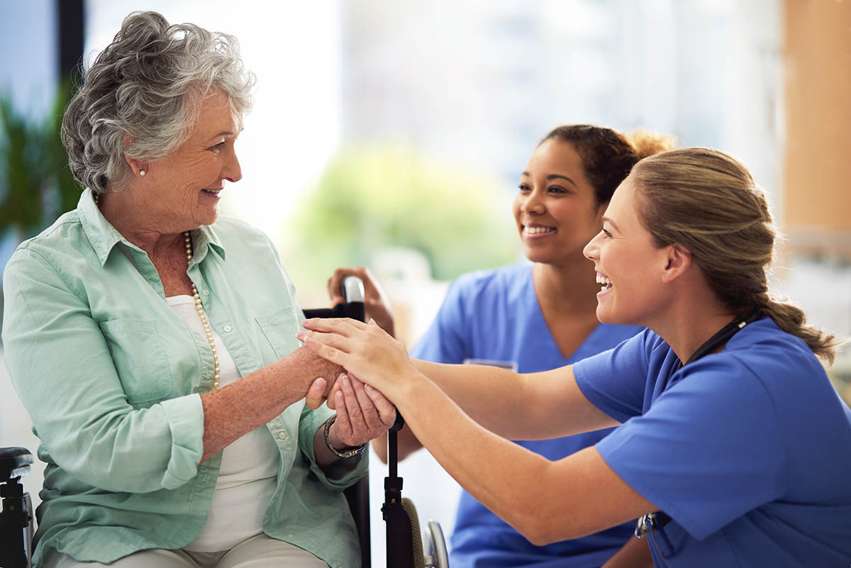 Jasmine Estates of Oklahoma City | tips for dementia caregivers | Shot of a smiling female doctor and nurse talking with a senior woman in a wheelchair | Higher Standard Memory Care Center in Oklahoma City | Full-Time RN Care & Medical Director | Safety in Memory Care: How Good Communities Protect the People They Serve