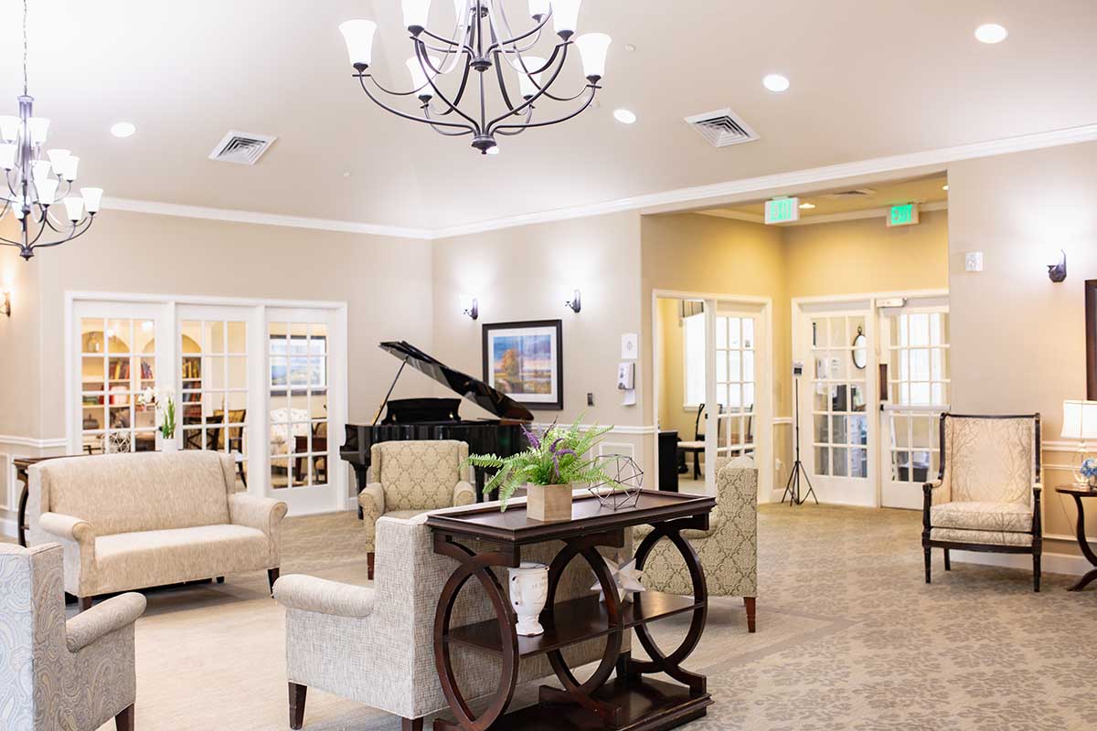 Jasmine Estates of Oklahoma City | Empty senior living living room with a piano in the corner