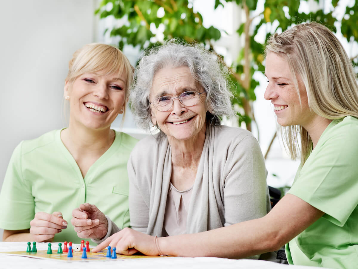 Jasmine Estates of Edmond | Senior woman and her two caregivers playing a game | memory care facilities | How to Tour a Memory Care Community: What to Look For, What to Ask, and What to Watch Out For