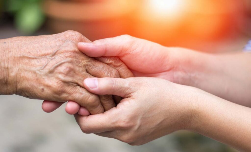 Jasmine Estates of Edmond | Senior holding hands with caregiver